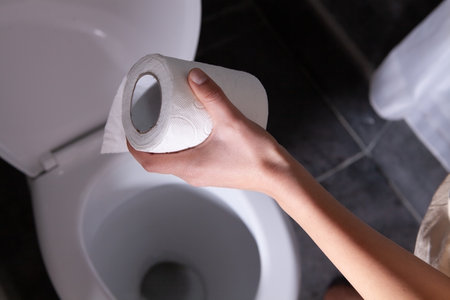 woman holding toilet paper in restroom. abdominal pain