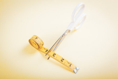 scissor cuts measuring tape on yellow backgroundの写真素材