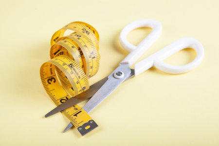 scissor cuts measuring tape on yellow backgroundの写真素材
