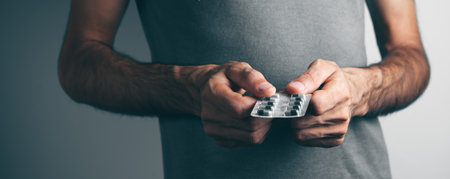 young man holding pills in handの写真素材