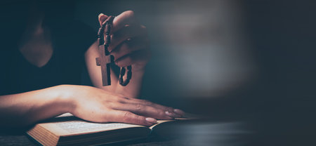 woman praying on book holding crossの写真素材