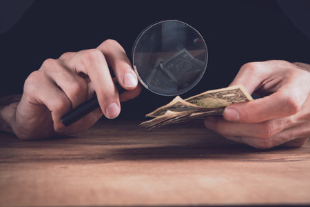 businessman holding a magnifying glass and moneyの写真素材