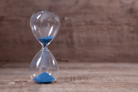 A side view of an hourglass with falling sand,