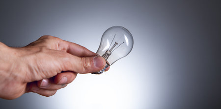 hand holding a light bulb on a black background