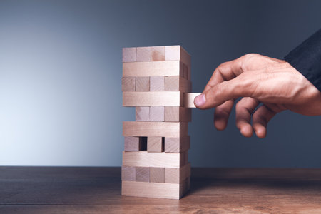 businessman hand holding wooden block tower with wood blocks.