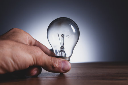 hand holding light bulb on wooden background