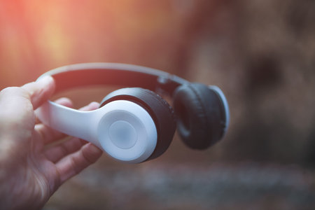 woman hand holding a wireless headphones with blurred background.の写真素材