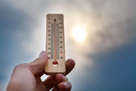 thermometer in hand on a background of a sky