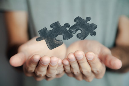 Hands holding jigsaw puzzle piece on dark background.