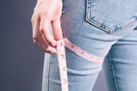 A woman in jeans measures her leg.の写真素材