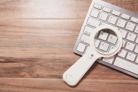 white computer mouse and a magnifying glass on a table.の写真素材