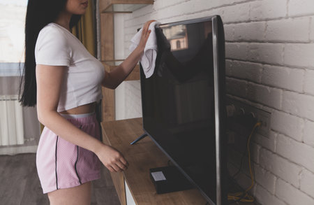girl in the living room cleaning with TV.の写真素材