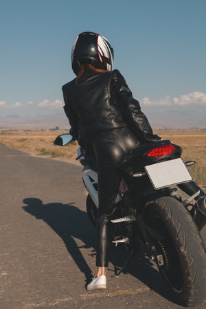 biker woman in a black jacket with a motorcycleの写真素材