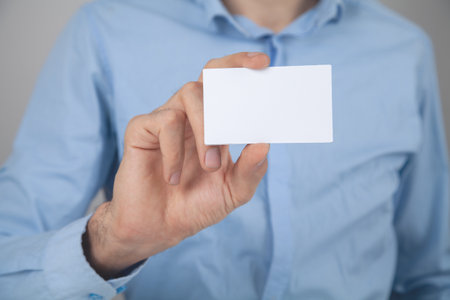 businessman holding blank white card on gray backgroundの写真素材