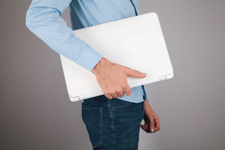 man in white shirt holding white laptop on gray backgroundの写真素材