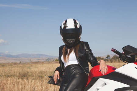 biker woman in a black jacket with a motorcycleの写真素材