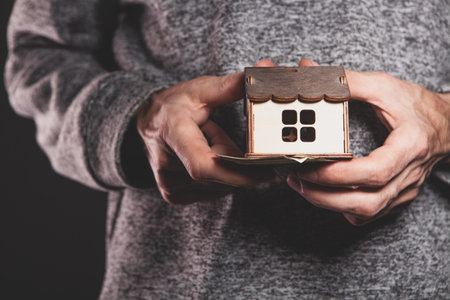 a man's hand holding a wooden toy houseの写真素材