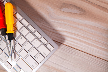 laptop with screwdriver and a white laptop on a wooden surface.の写真素材