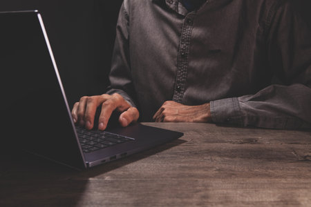 man in a white shirt is typing on a black computer keyboardの写真素材