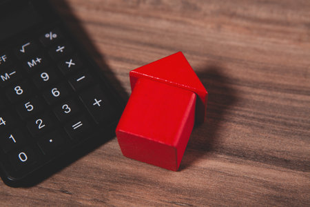 calculator on a wooden table with a red house background.の写真素材