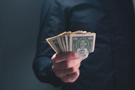 man with money. businessman in black suit holds a bundle of dollars.の写真素材
