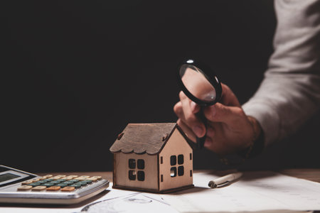 man holding a calculator and house model on desk, mortgage and loan loan conceptの写真素材