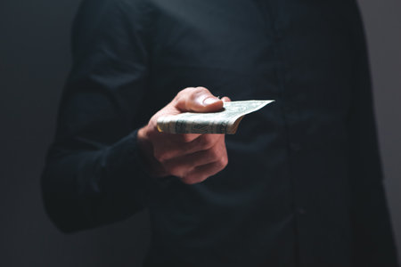 man with money. businessman in black suit holds a bundle of dollars.の写真素材
