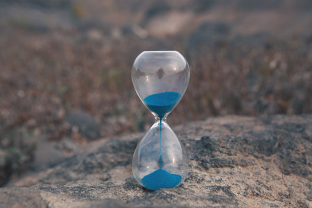 a closeup of an hourglass in a sand on blurry backgroundの写真素材