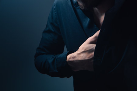 young man with a beard and a black shirt in a black jacket on a dark backgroundの写真素材