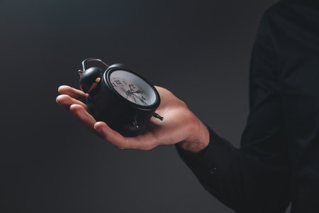 hand of man holding clock on black background. time management conceptの写真素材