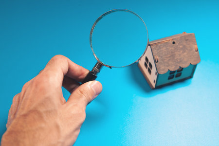 magnifying glass in hand of house on blue background, cの写真素材