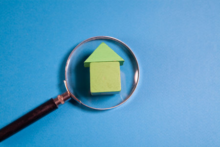 House model under a magnifying glass on a blue background. The concept of buying or selling real estate.の写真素材