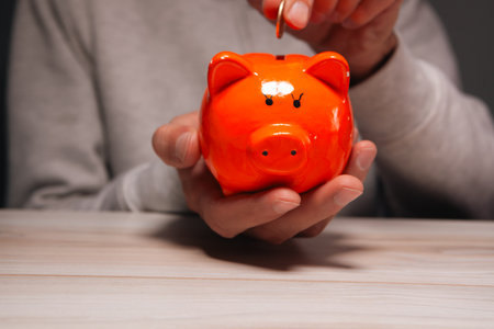 hand putting a coin in a piggy bank on a white background, money saving concept.の写真素材