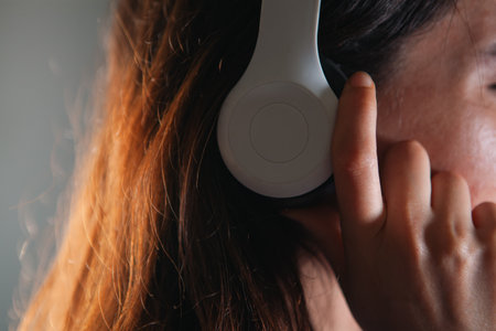Close up of a woman with headphones listening to music on a gray backgroundの写真素材