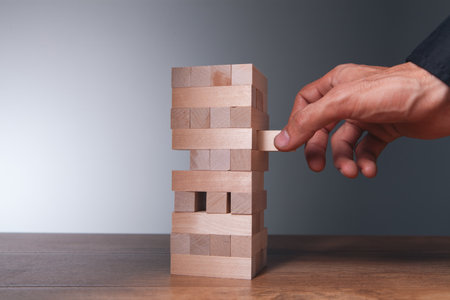 Businessman placing wooden block on the tower, risk and management concept