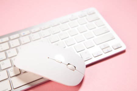 white mouse on a white keyboard with a pink background