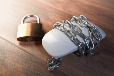 computer mouse with chain and padlock on wood background, security concept