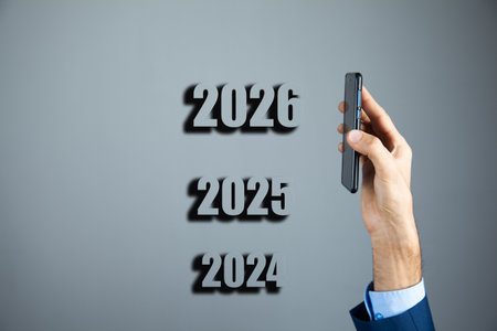 businessman hand holding mobile phone with 2026 new year text on gray background
