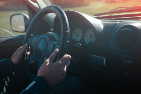 Close up of a man driving a car, hands on steering wheel