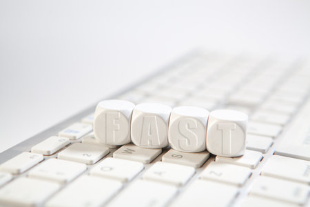FAST word made with building blocks on computer keyboard and white backgroundの写真素材