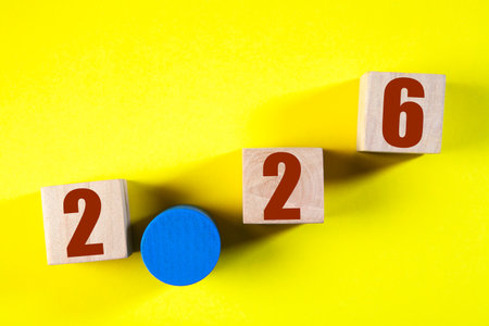Wooden blocks with numbers of year 2026 on a yellow background. Copy space.