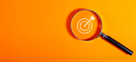 Magnifying glass with new year goals and target on orange backgroundの写真素材
