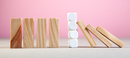Domino effect with wooden blocks on a pink background. Business conceptの写真素材