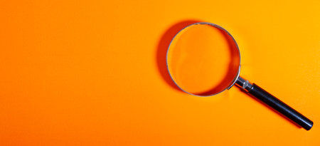 Magnifying glass on orange background. View from above with copy spaceの写真素材