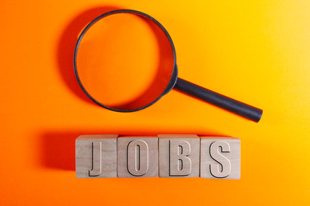 Jobs word on wooden cubes with magnifying glass on orange backgroundの写真素材