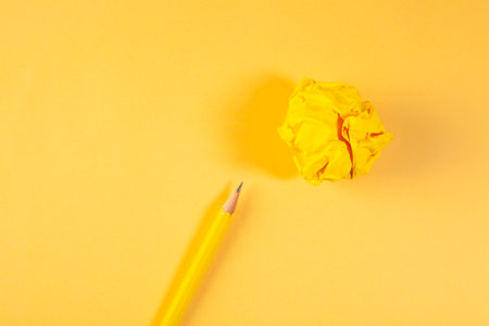 Yellow crumpled paper ball and a pencil on a yellow backgroundの写真素材