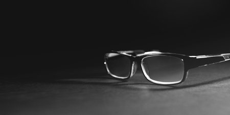 Black and white photo of eyeglasses on a black background.の写真素材