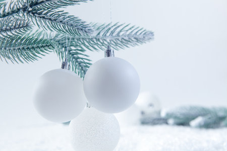 White christmas balls on a spruce branch on a white backgroundの写真素材