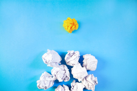 White crumpled paper ball and yellow paper ball on blue backgroundの写真素材