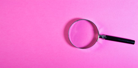 Magnifying glass on pink background. Top view with copy space.の写真素材